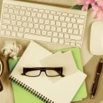 Messy office table with notepad, computer, reading glasses and coffee cup. View from above with copy space