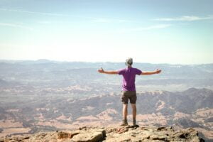 a man with outstretched arms at a summit to symblolise job seeking tips leading to success 