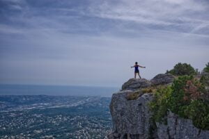 a woman standing on a mountain with outstretched arms to symbolise the firm's future being your responsibility